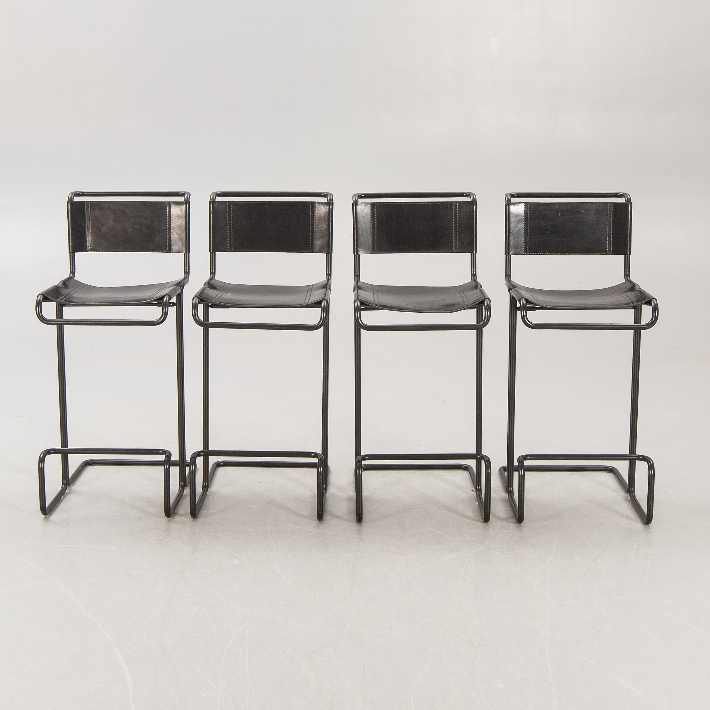 A set of four leather and metal bar stools later part of the 20th