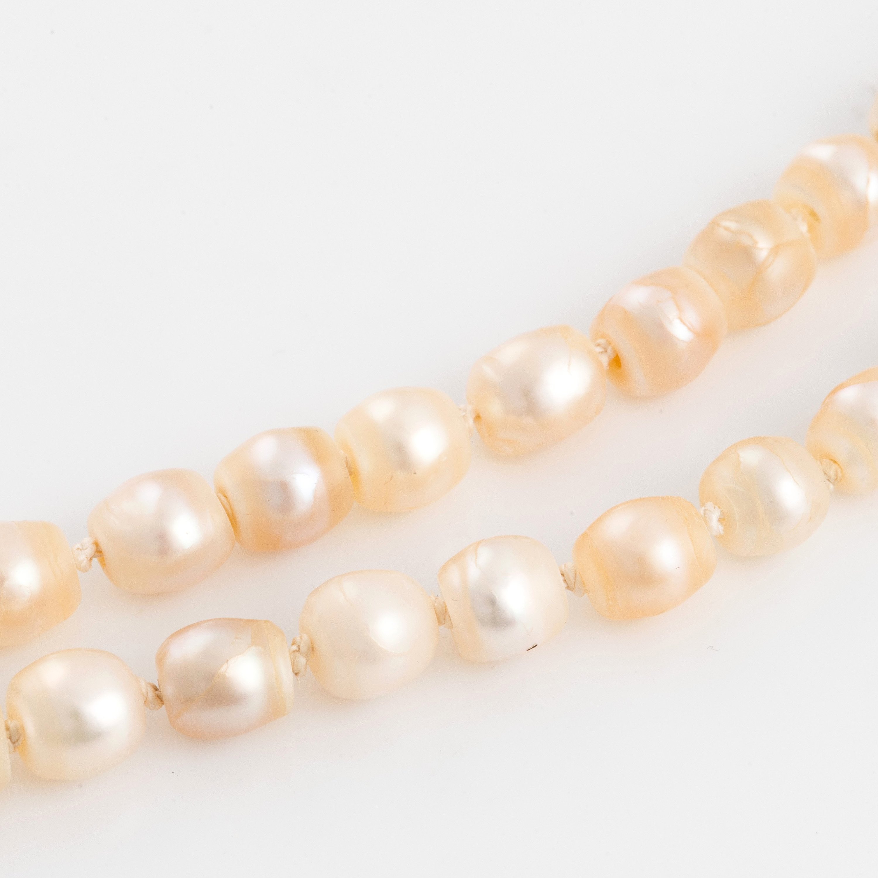 A two strand natural pearl necklace with a silver clasp set with an old