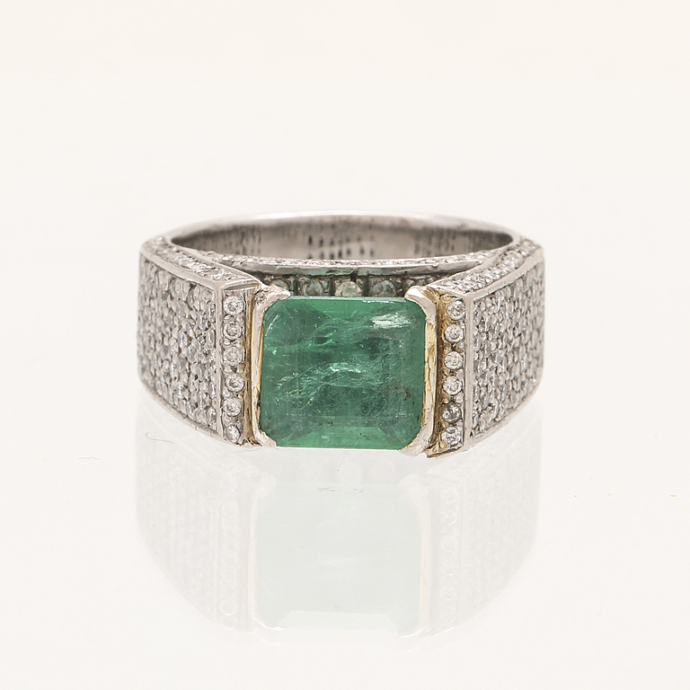 A 9K white gold ring with an emerald and brilliant cut diamonds.