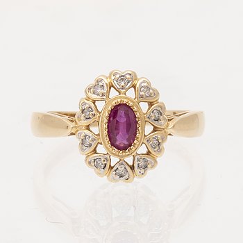 An 18K gold ring set with an oval brilliant cut ruby and round brilliant cut diamonds.