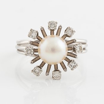 An 18K gold ring set with a cultured pearl and round brilliant-cut diamonds.