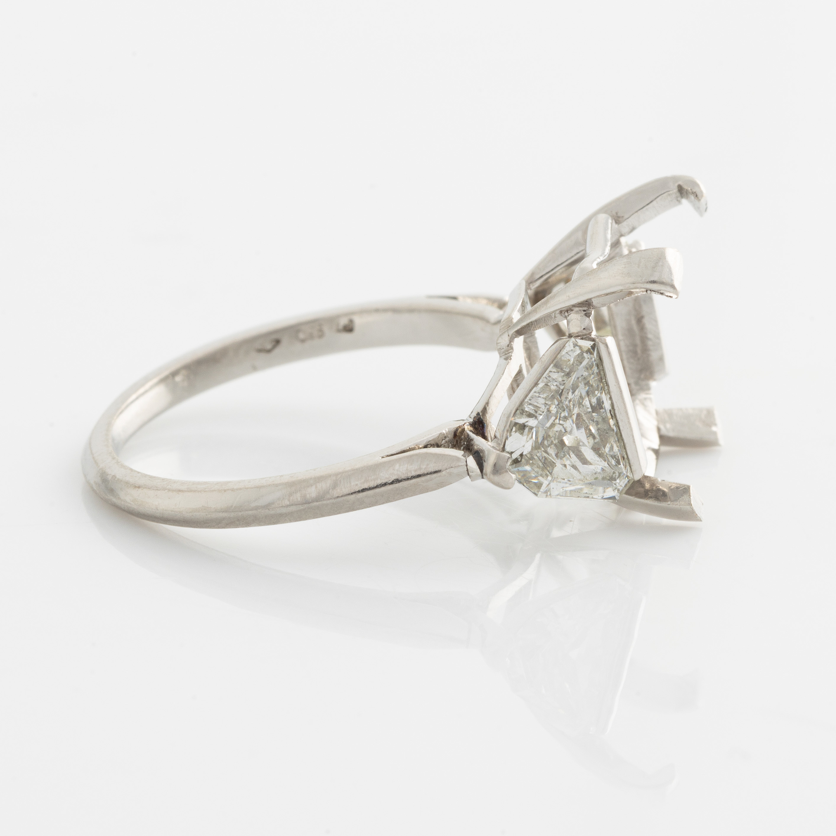 A platinum ring with and empty setting and with two triangular step cut ...