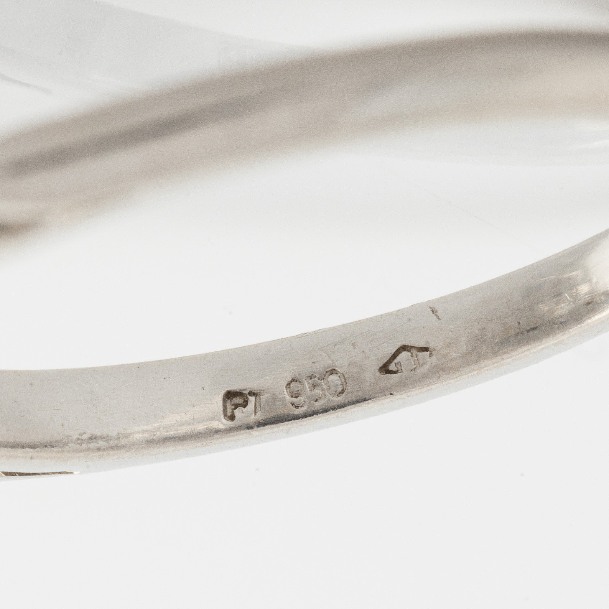 A platinum ring with and empty setting and with two triangular step cut ...