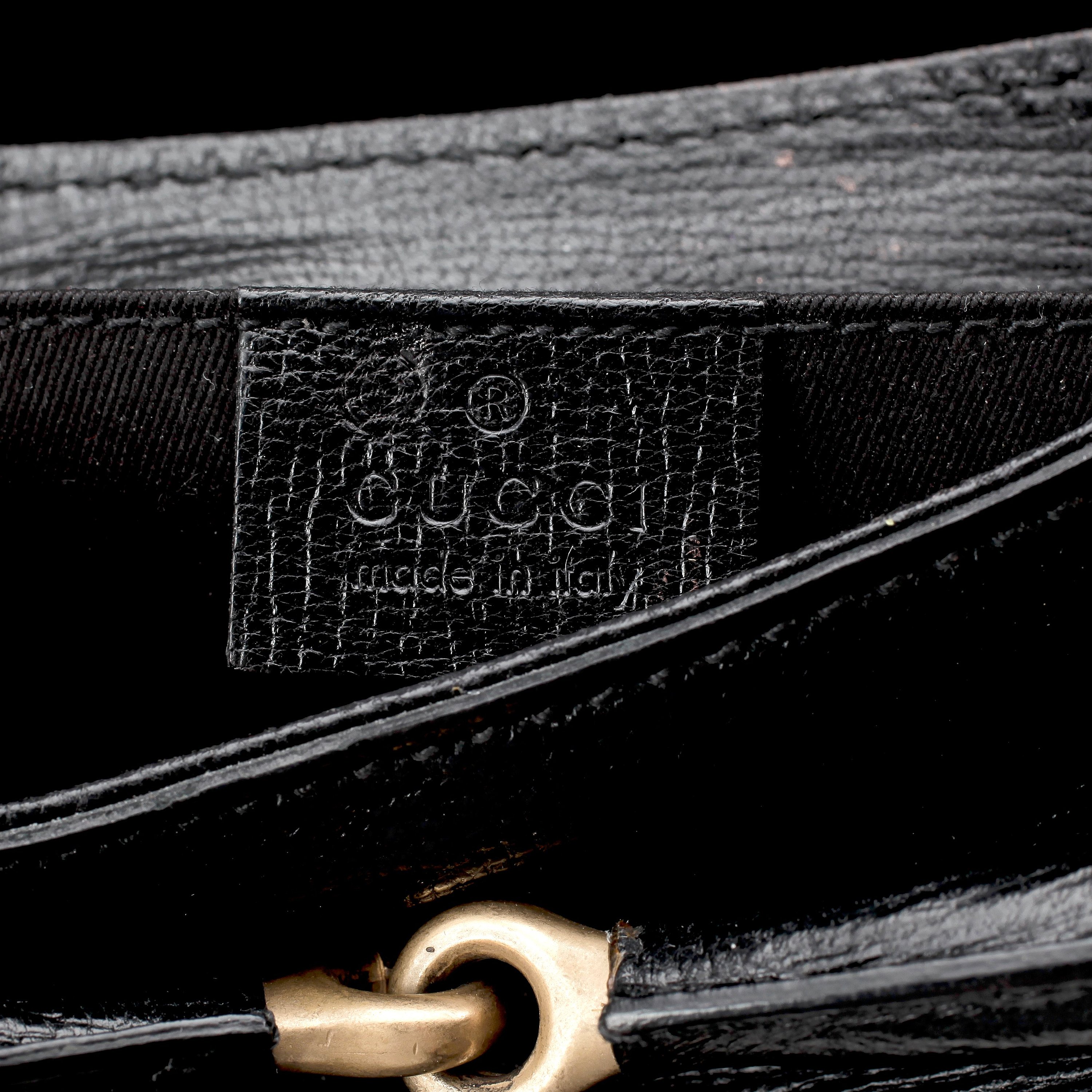 GUCCI, a black embossed leather clutch with a shoulder strap. Bukowskis